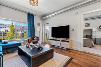 Living room with large window and exposed ductwork